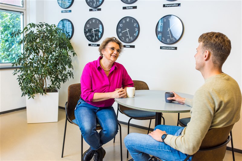 Twee collega’s in gesprek aan tafel met koffie