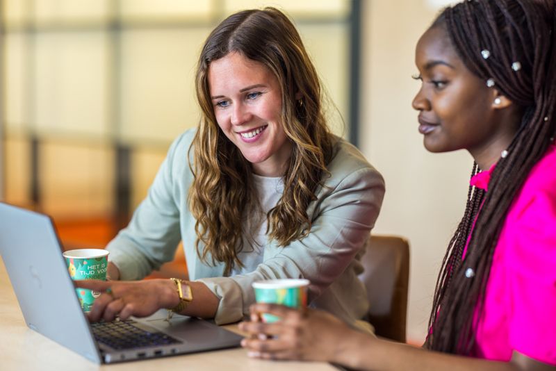 Een medewerker wijst collega iets aan op haar laptop